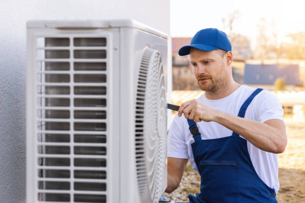 HVAC technician servicing an outdoor air conditioner in Compton